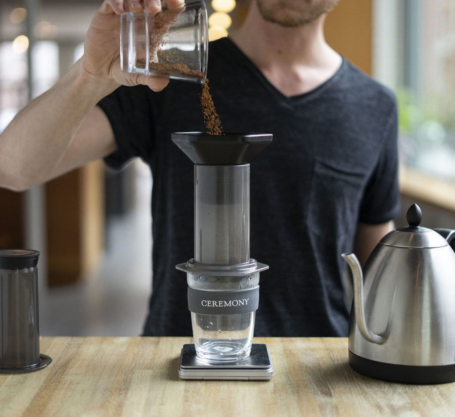 A person pouring coffee into a coffee grinder