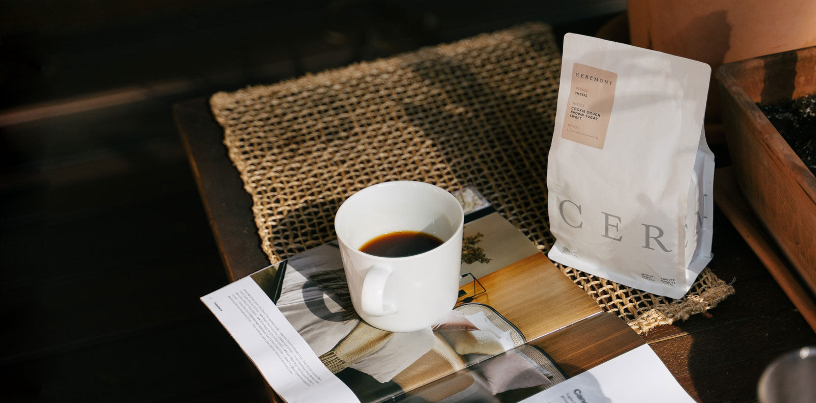 A cup of black coffee next to a 12 oz bag of Ceremony beans.