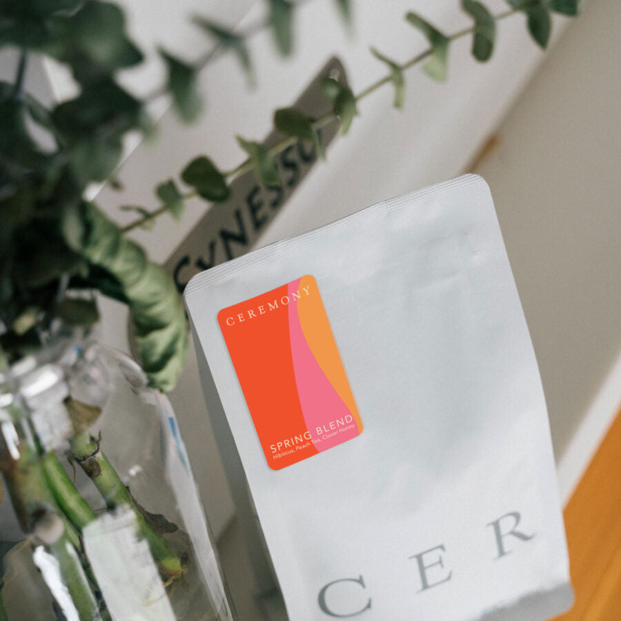 A white bag with a label on it next to a glass vase with a plant